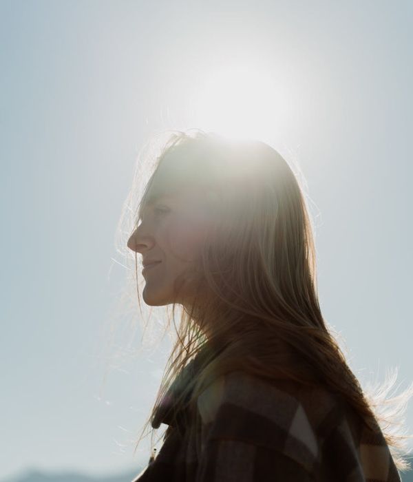 Smiling person stretching outdoors under the morning sun.